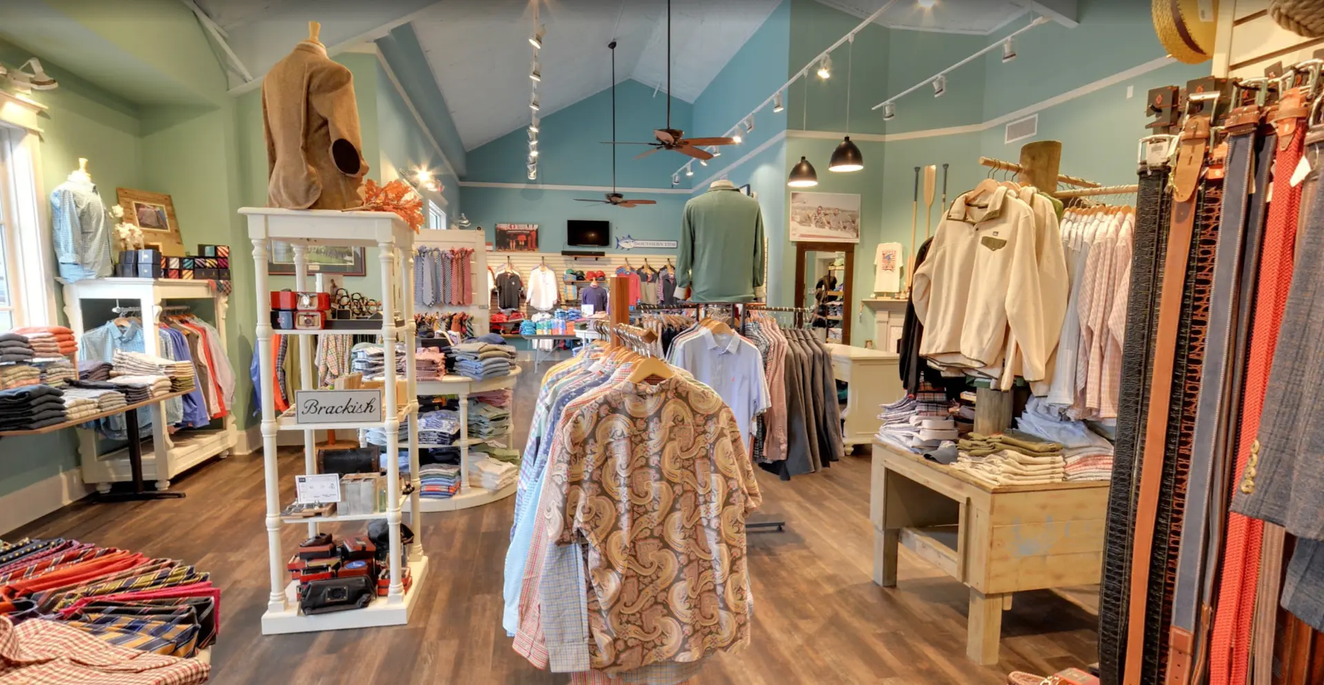 Inside Low Country Clothier: sport shirts, ties, belts, and folded knits arranged across wood tables and racks