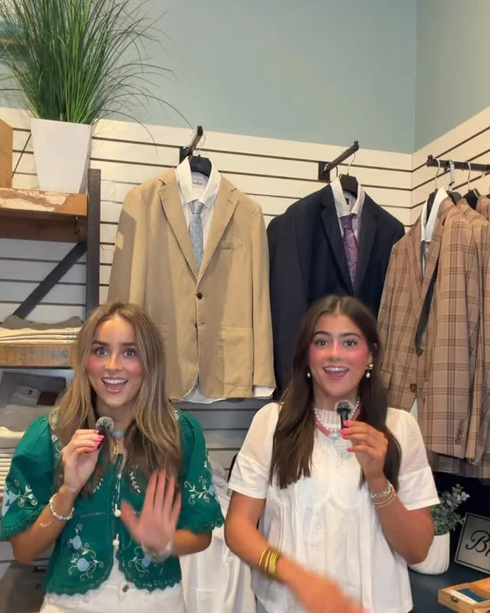 Two Low Country Clothier staff members on the sales floor in front of a rail of sport coats and suits